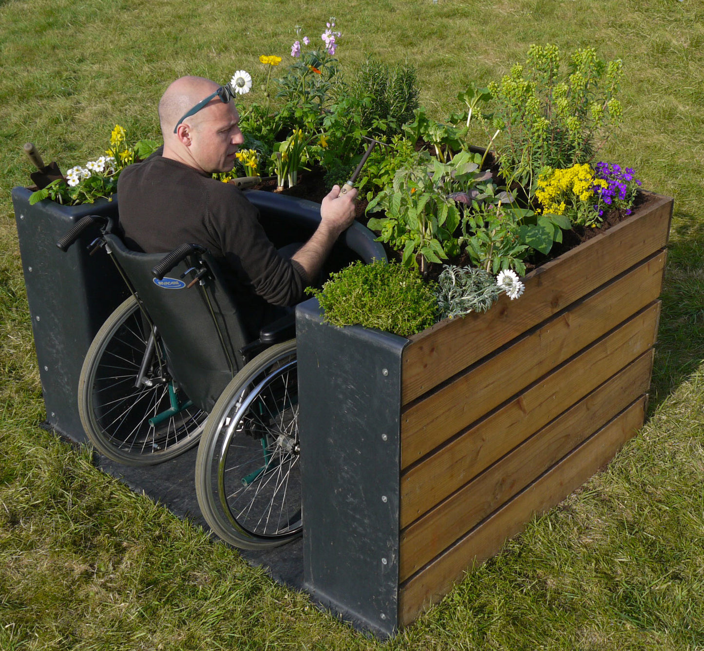 Bac de jardin en bois sur lequel une fixer une coque en plastique qui laisse entrée une chaise roulante.