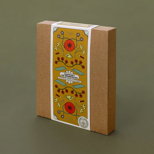 Boîte sur laquelle on lit « Coffret de semences : Variétés ancestrales du Québec ». On y voit des dessins de tomates, haricots, feuilles de courges et rhubarbe.